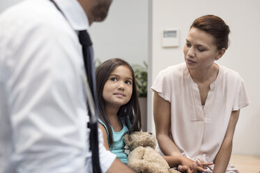 Mutter sieht Mädchen an, das dem Arzt zuhört, während es im Krankenhaus sitzt - CAVF38495