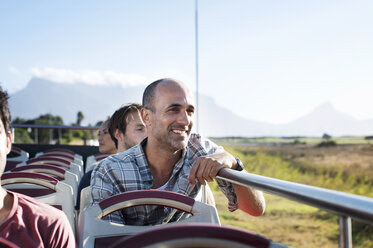 Touristen betrachten die Aussicht während der Fahrt im Doppeldeckerbus gegen den Himmel - CAVF38517