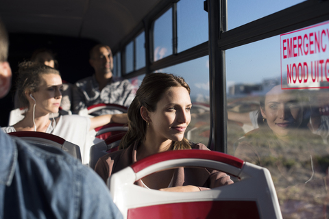 Fahrgäste schauen durch das Fenster, während sie in einem Reisebus unterwegs sind, lizenzfreies Stockfoto