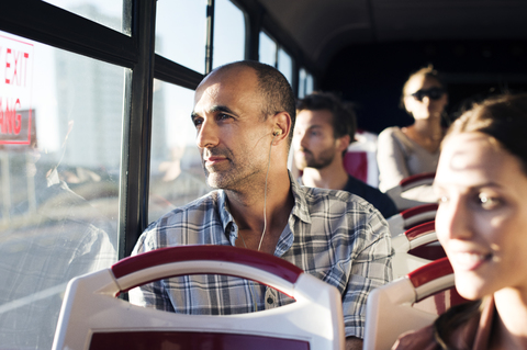 Fahrgäste schauen durch das Fenster, während sie im Bus unterwegs sind, lizenzfreies Stockfoto