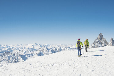 Rückansicht von Wanderern, die auf einem schneebedeckten Berg gegen einen klaren blauen Himmel wandern - CAVF38533