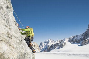 Seitenansicht eines Wanderers beim Klettern auf einen Berg gegen einen klaren blauen Himmel im Winter - CAVF38543