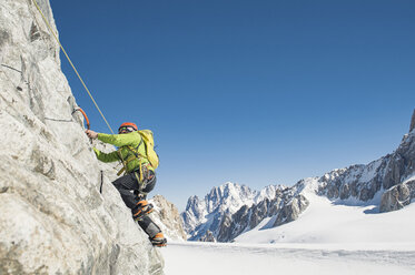 Side view of hiker climbing mountain against clear blue sky during winter - CAVF38543