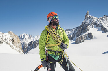 Wanderer mit Kletterausrüstung auf einem schneebedeckten Berg vor blauem Himmel - CAVF38544