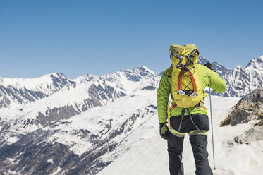 Rückansicht eines Wanderers, der einen schneebedeckten Berg gegen einen klaren blauen Himmel an einem sonnigen Tag besteigt - CAVF38550