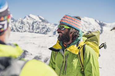 Smiling hikers standing on snow covered mountain during sunny day - CAVF38552