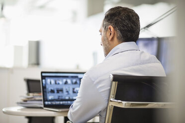 Rear view of businessman working at desk in office - MASF04609