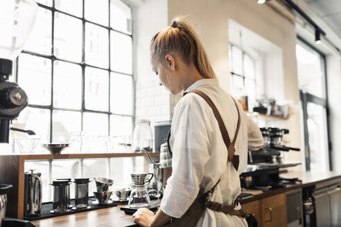 Rückansicht eines Barista, der am Tresen Kaffee zubereitet - MASF04665