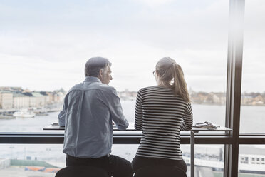 Rückansicht von Geschäftsleuten, die am Schalter am Fenster im Büro sitzen - MASF04670