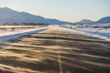 Country road moving towards snowcapped mountains against clear sky - CAVF38673