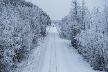 Fernansicht eines Fahrzeugs auf schneebedeckter Straße zwischen Bäumen - CAVF38684