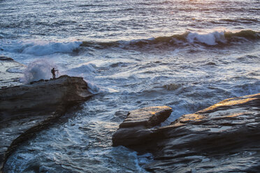 High angle view of person standing on rocks by sea at Cape Kiwanda State Park - CAVF38762