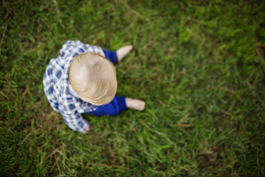 Draufsicht auf ein Baby, das auf einer Wiese im Park sitzt - CAVF38786