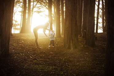 Mutter, die einem kleinen Jungen beim Gehen im Wald hilft - CAVF38792