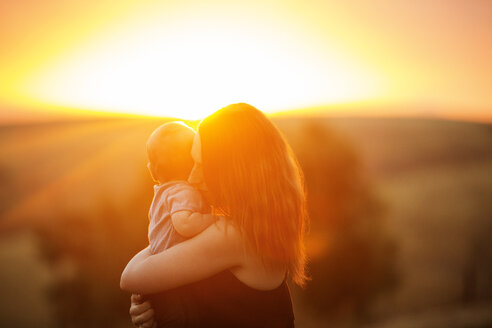 Seitenansicht einer Mutter mit Baby bei Sonnenuntergang - CAVF38794