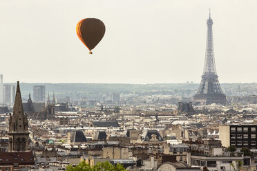 Hot air balloon flying over cityscape with Eiffel Tower in background - CAVF38866