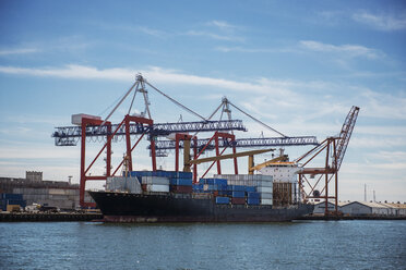 Container ship moored at commercial dock against sky - CAVF38884