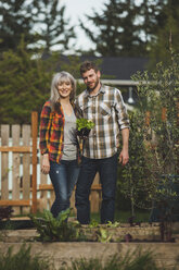 Porträt eines lächelnden Paares mit Pflanzen im Hinterhof - CAVF38934