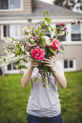 Frau hält einen Blumenstrauß auf einem Feld stehend - CAVF38948