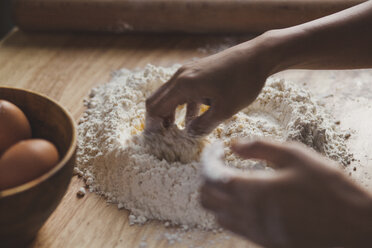 Cropped image of woman kneading dough on table in kitchen - CAVF38958