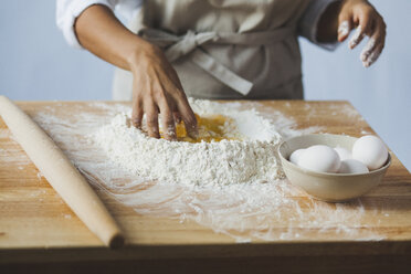 Midsection of woman kneading dough on table while standing in kitchen - CAVF38969