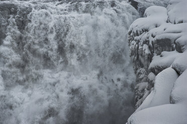 Scenic view of waterfall by snow covered cliff - CAVF38984