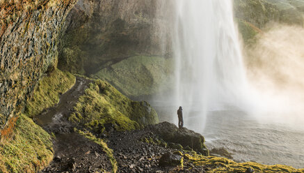 Rückansicht eines Mannes, der auf einem Felsen am Wasserfall steht - CAVF39026