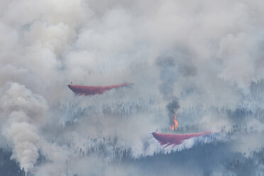 Blick von oben auf ein Wasserflugzeug, das Wasser auf einen Waldbrand abgibt - CAVF39033