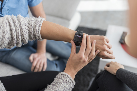 Frauenhand stellt Smartwatch am Schreibtisch ein, lizenzfreies Stockfoto