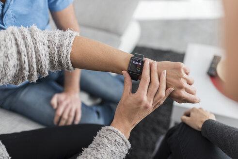 Frauenhand stellt Smartwatch am Schreibtisch ein - PAF01821