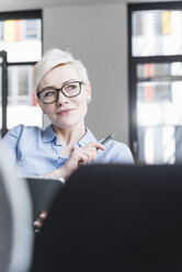 Porträt einer lächelnden Frau mit Brille im Büro - UUF13356