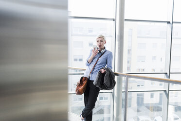 Frau in Bürogebäude mit Mobiltelefon - UUF13380