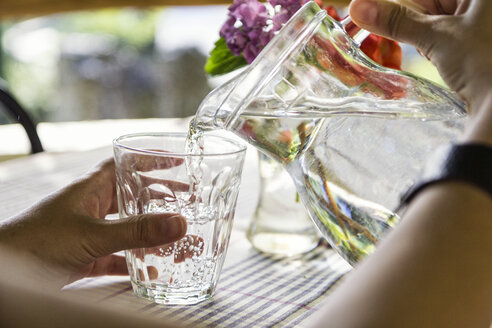 Frauenhände gießen Wasser in ein Glas, Nahaufnahme - MAMF00047