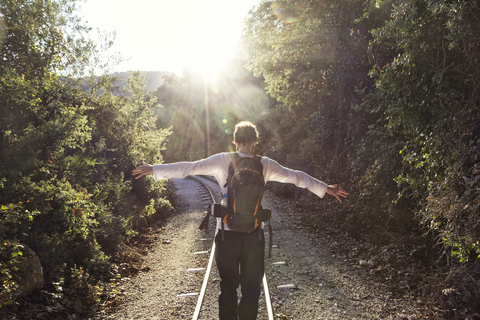 Greece, Pilion, Milies, back view of man with backpack balancing along rails of Narrow Gauge Railway stock photo