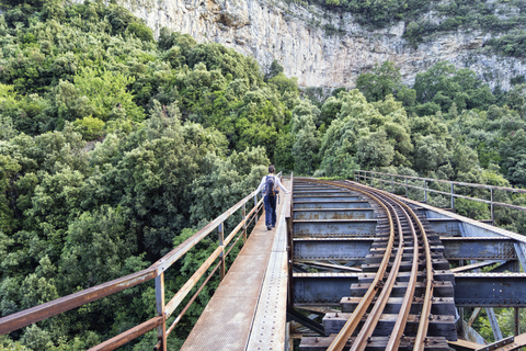 Griechenland, Pilion, Milies, Rückenansicht eines Mannes, der auf einer Brücke entlang der Schienen der Schmalspurbahn geht, lizenzfreies Stockfoto