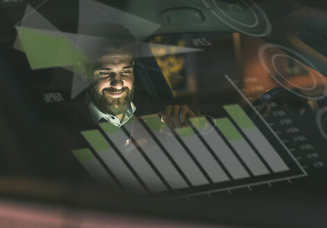 Lächelnder Geschäftsmann mit Smartphone im Auto bei Nacht, umgeben von Daten - UUF13404