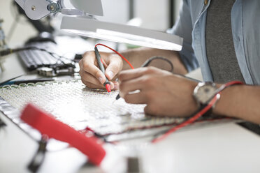 Close-up of engineer soldering circuit at table in electronics industry - CAVF39076