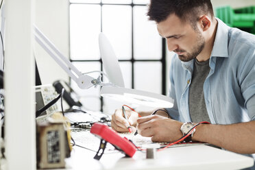 Concentrated engineer soldering circuit at table in electronics industry - CAVF39077