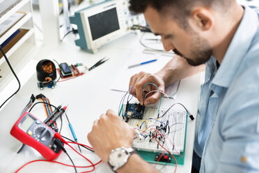 High angle view of technician analyzing circuit board at table - CAVF39080