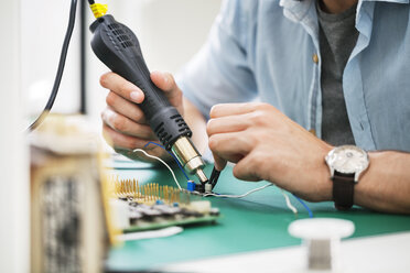 Midsection of technician working at table in electronics industry - CAVF39083