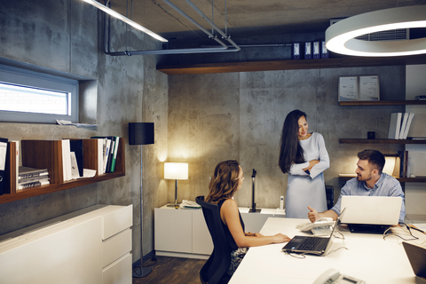 Geschäftsleute, die am Schreibtisch im Büro diskutieren, lizenzfreies Stockfoto