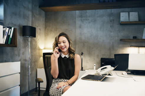 Glückliche Geschäftsfrau mit Smartphone im Büro - CAVF39112