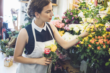 Blumenhändlerin pflückt Rosen aus Vasen im Geschäft - CAVF39151