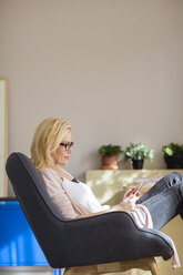 Seitenansicht einer Frau, die einen Tablet-Computer benutzt, während sie sich zu Hause entspannt - CAVF39205