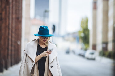 Woman using mobile phone while standing on city street - CAVF39227