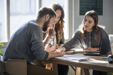 Universitätsstudenten, die am Tisch im Klassenzimmer sitzen und lernen - CAVF39233