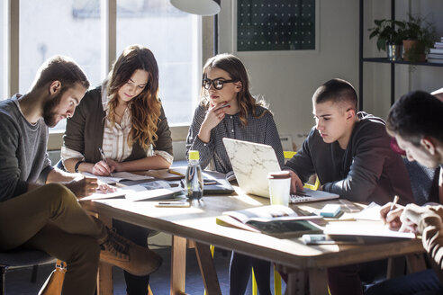 College-Studenten, die am Tisch am Fenster im Klassenzimmer sitzen und lernen - CAVF39238