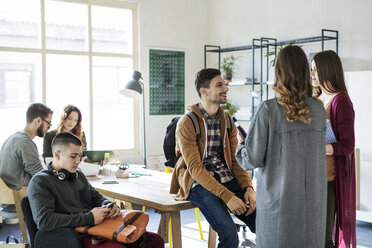 Studenten im Gespräch mit Freunden, die am Tisch im Hintergrund lernen - CAVF39264