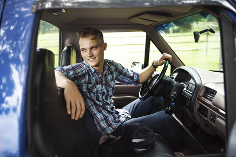 Glücklicher Mann, der wegschaut, während er in einem Pick-up-Truck sitzt, lizenzfreies Stockfoto