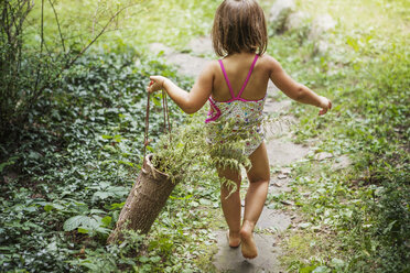 Rückansicht eines Mädchens, das einen Holzkorb mit Pflanzen trägt - CAVF39413